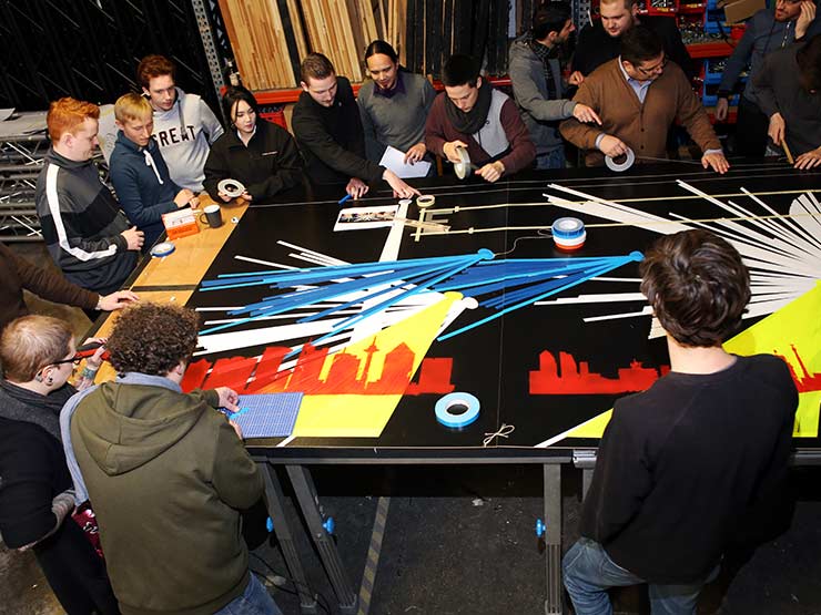 Foto einer Gruppe von Teilnehmern eines Street Art Workshops erstellen gemeinsam ein großflächiges Tape Art Werk.